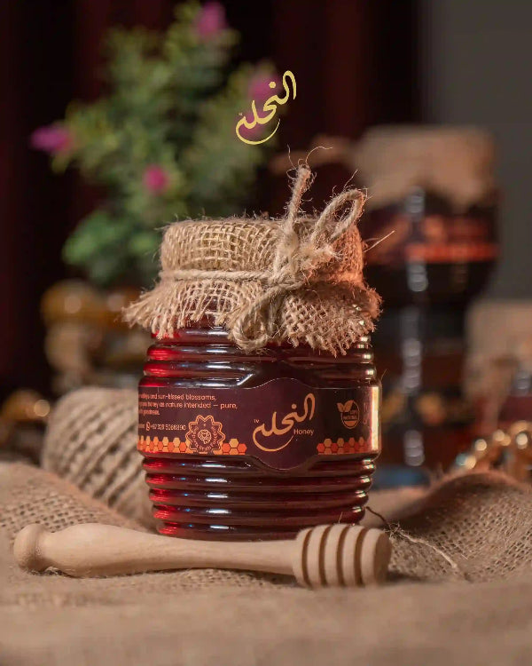 Jar of annahla honey with a wooden dipper on a textured surface, blurred background